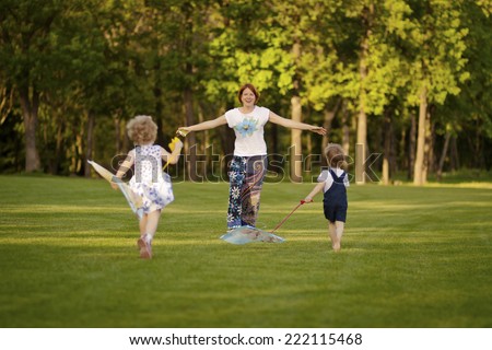 Mom with kids playing in the park. Children run to meet mom