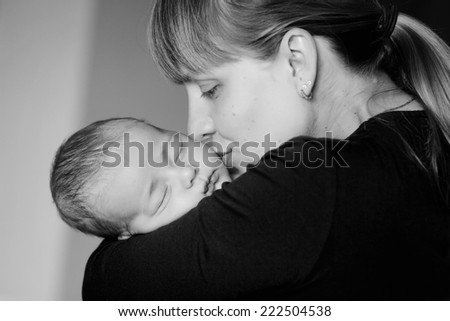 Sleeping baby on the mother's hands. Young mother shakes her baby in her arms and kisses him