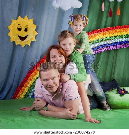 Beautiful family on the lawn on a bright rainbow background with clouds and sun