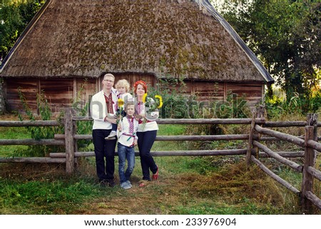 Ukrainian family in national clothes near ethnic house, Ukraine, open-air museum Pirogovo