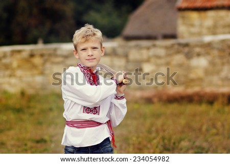 Ukrainian blond boy in national clothes with a sword. Ukrainian tradition, national character. Ukraine, Kiev, a museum open-air Pirogovo