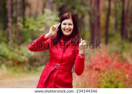 Attractive young woman talking on the phone in nature. Joyful emotions of good news, the gesture \