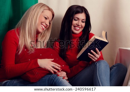 Two attractive young women read with interest the book, fun, leisure, socializing and friends