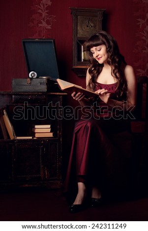 Young woman in vintage interior reading a book and listening to the gramophone, retro, vintage