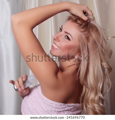 Attractive young blonde woman after a shower, wrapped a towel with deodorant.