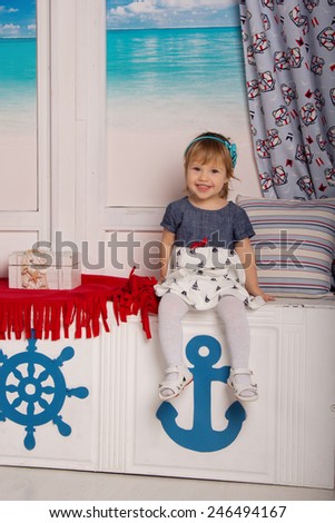 Little cheerful girl sailor in the sailor interior. Carefree childhood, game, entertainment