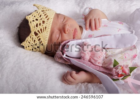 Sleeping newborn baby in a crown with a toy. Tenderness, peace
