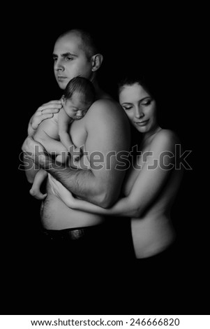Beautiful mother and father holding their newborn baby. The concept of parenting, care, care. Black background, black and white image