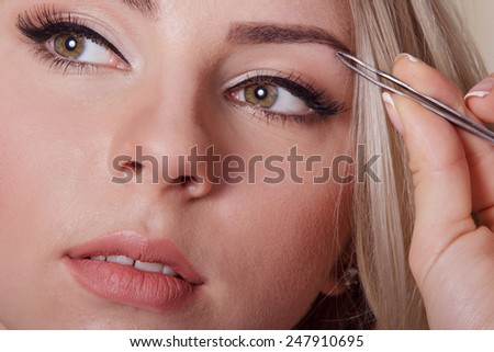 Joyful fresh blonde woman plucking her eyebrows