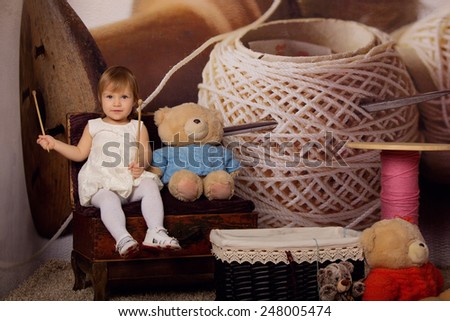 Cute little girl in the original interior of the thread. Knitting, hobby, early childhood development