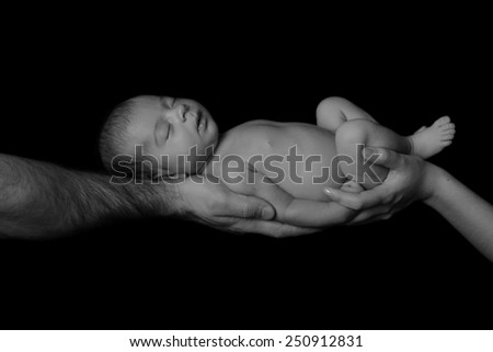 Sleeping newborn baby in her arms mom and dad. Concept of love, protection of children. Studio, black background. black and white photography