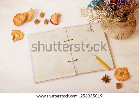 The composition of the vase on the table with dried flowers, apples and old notebook. Retro, vintage