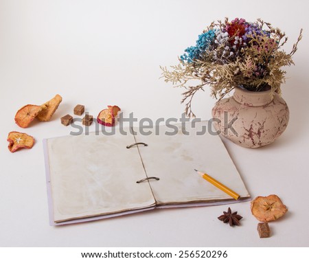 The composition of the vase on the table with dried flowers, apples and old notebook. Retro, vintage