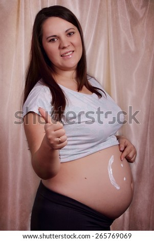 Happy pregnant woman smeared cream on stomach, stretch marks cream, smile cream