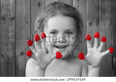 Cheerful child with a raspberries fingers. Food, fun, healthy food