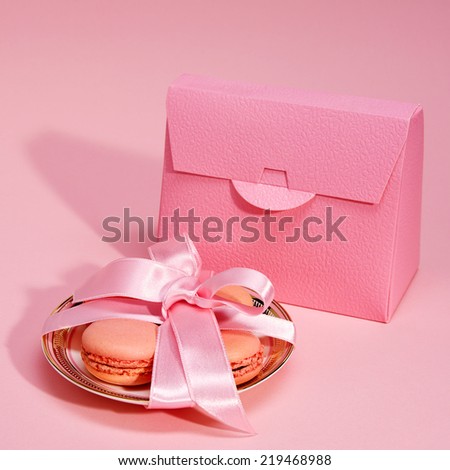 Cookies decorated with a ribbon and gift envelope on pink background