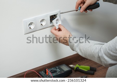 A young electrician installing an electrical plug in a new house.