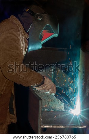 A tradesman welding steel on site at a engineering site at a mine. The sparks from the arc light the gloves and elding shield helmet.
