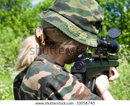 The young girl in a camouflage, aims from a telescope-sighted rifle