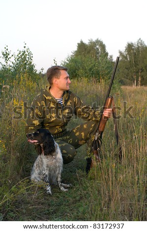 Man in camouflage with a gun and russian hunting spaniel.
