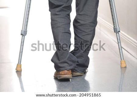 Man walking with crutches in hospital corridor