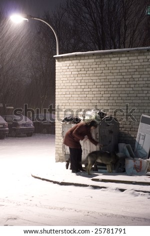poor woman  rummaging in garbage dumpster on winter night