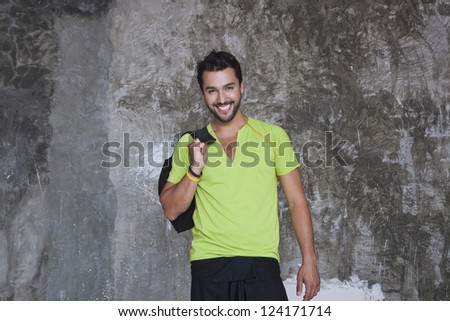 Portrait of a man smiling with holding a bag in front of a rock