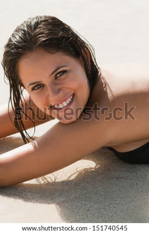 Close up of woman lying on the sand smiling looking at camera