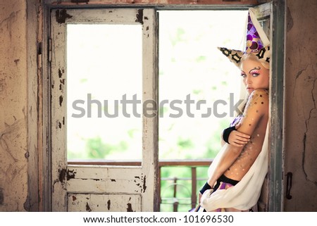 Girl in a fairy-tale image stands at the window