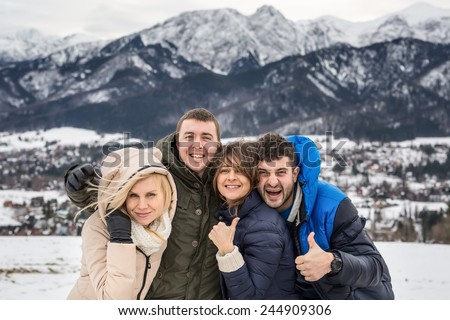 Two beautiful young couple on the background of the Polish Tatras. two women two men m. Snow-capped mountains. Winter photo. Two show the face of the camera.
