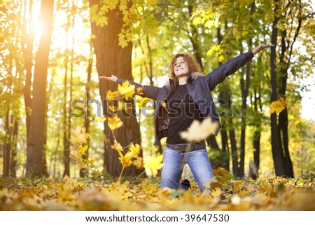 Young woman playing in autumn park leaves