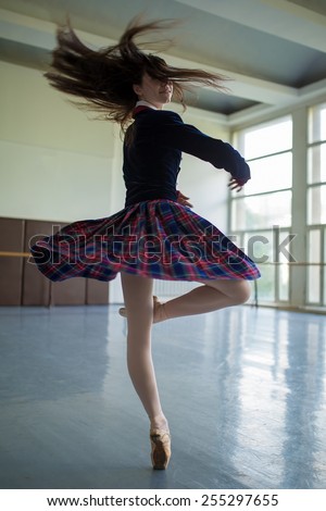 Long-haired ballerina spins in the dance moves on one leg to stand on pointe.