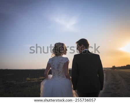 Young wedding couple talking on the field at sunset. Newlyweds back to Kemer look at each other.