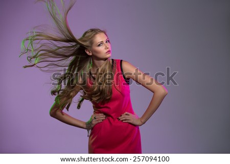 Studio portrait of long-haired girl in bright pink background with flying hair in the wind.