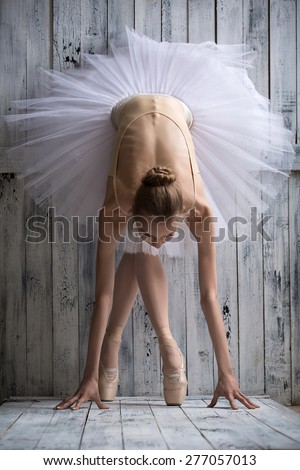 Ballerina dressed in white tutu makes lean forward
