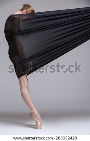 Slim dancer plays with black mesh fabric