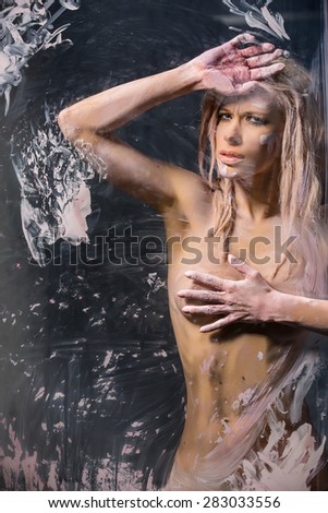 Portrait of seminude blonde through the glass smeared pink clay