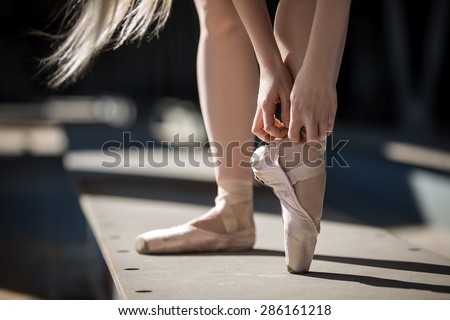 Legs ballerina closeup. Dancer tying pointe shoes.