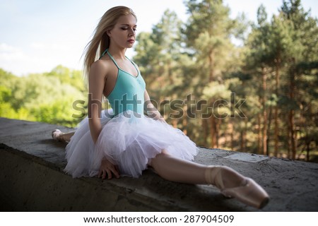 Graceful ballerina in white tutu sitting on the splits