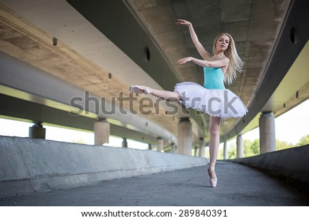 Graceful ballerina doing dance exercises on a concrete bridge