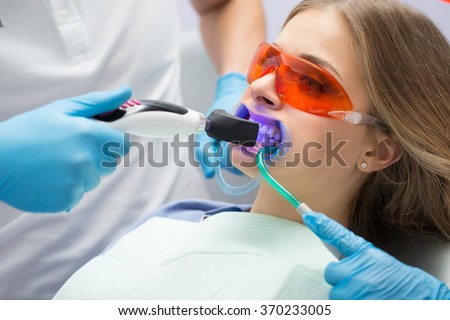 Girl patient in the dental clinic. Teeth whitening UV lamp with photopolymer composition.