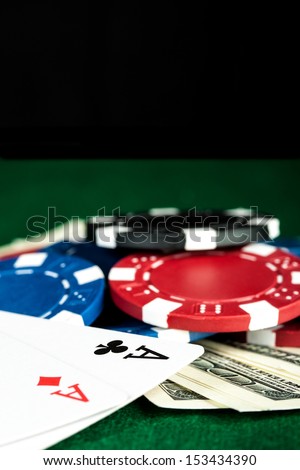 Group of chips, money and poker cards on the green cloth.