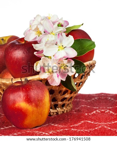 red apples and flowers in wicker basket on red tablecloth. country style