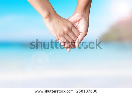 Hands of two people off the beach on summer background blur.