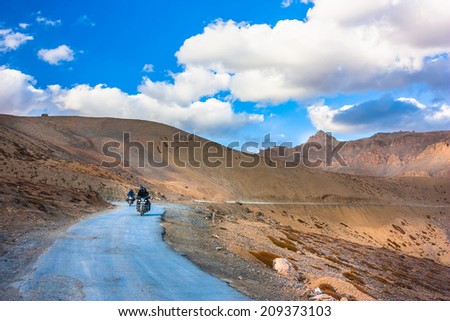 Motor bikers ride road in the high mountains. Background blue sky with clouds, Himalayas, Indian Tibet