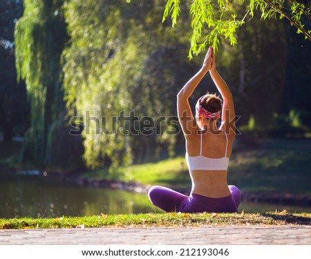 Young woman doing yoga in Park near lake