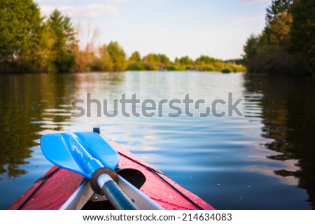 Two blue paddles are lying on kayak. Kayaking on a river.