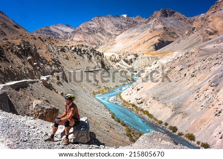 Bicyclist sitting on mountains road. Himalayas, Jammu and Kashmir State, North India