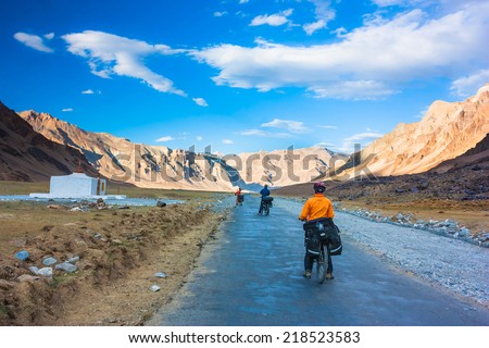 Three cyclist standing on mountains road. Himalayas, Jammu and Kashmir State, North India