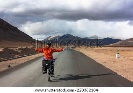 Bicyclist riding in storm fantastic landscape on mountain road, Jammu and Kashmir State, North India